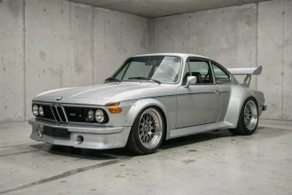 BMW 3.0 CSL coupé argenté polaris dans un garage minimaliste en béton, vue 3/4 avant avec spoilers aérodynamiques et jantes BBS d'époque