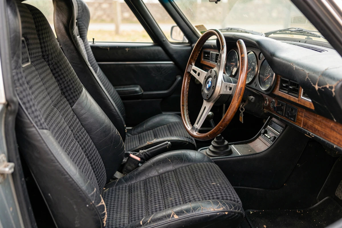 Intérieur cockpit de la BMW 3.0 CSL avec sièges baquets Scheel en tissu pied-de-poule, volant en bois et tableau de bord d'origine en détail