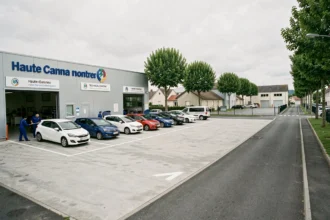 Vue large d'un centre de contrôle technique en Haute-Garonne avec des voitures en attente et des techniciens en uniforme